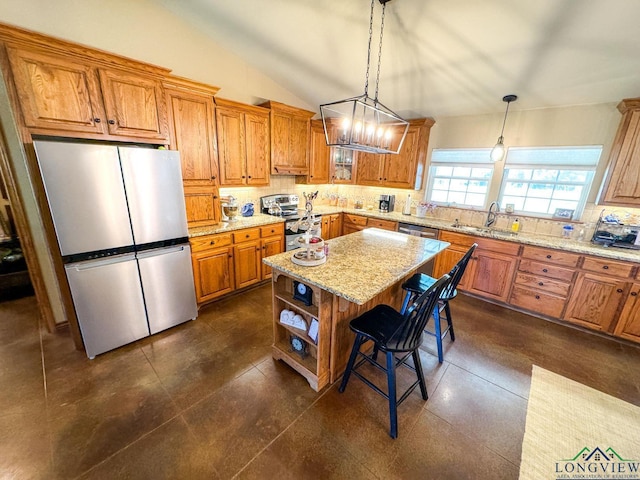 kitchen featuring a kitchen bar, appliances with stainless steel finishes, sink, a kitchen island, and hanging light fixtures