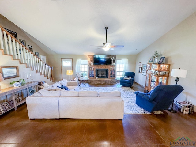 living room featuring ceiling fan and a stone fireplace