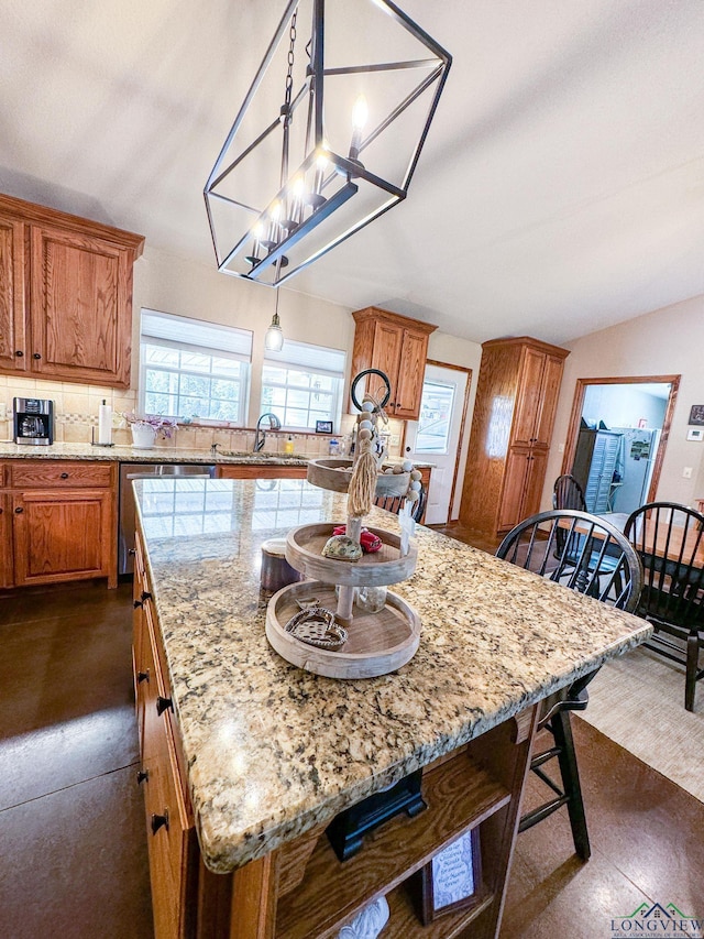 kitchen featuring hanging light fixtures, tasteful backsplash, light stone counters, a breakfast bar, and a kitchen island