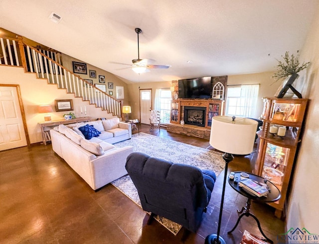 living room with a stone fireplace, ceiling fan, and a healthy amount of sunlight