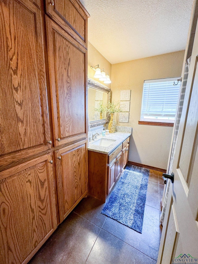 bathroom with tile patterned flooring, a textured ceiling, and vanity