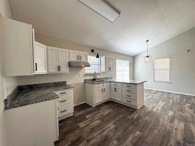 kitchen with white cabinetry, dark hardwood / wood-style floors, decorative light fixtures, vaulted ceiling, and kitchen peninsula