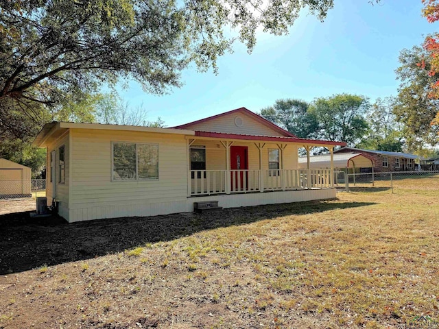 view of front of house with central AC, covered porch, and a front lawn