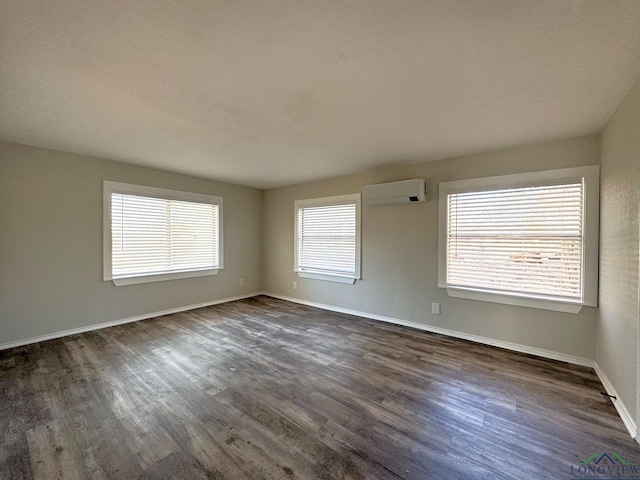 spare room with an AC wall unit and dark hardwood / wood-style flooring