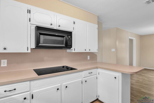 4202 Brent Rd, Longview, TX 75604 - kitchen with black appliances, a peninsula, light countertops, and white cabinetry