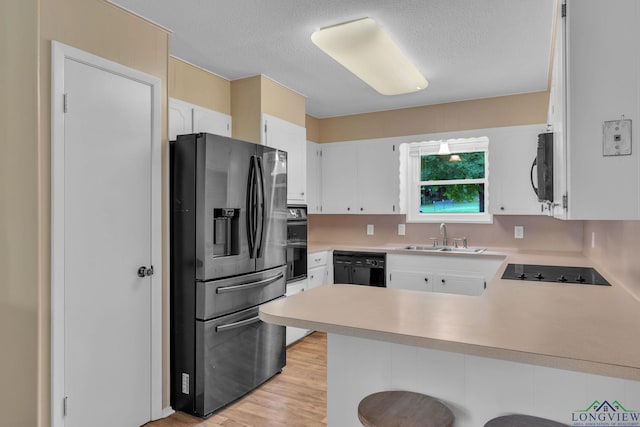 4202 Brent Rd, Longview, TX 75604 - kitchen with black appliances, a sink, a peninsula, light countertops, and light wood-style floors