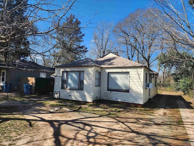 view of property exterior featuring cooling unit, roof with shingles, driveway, and fence