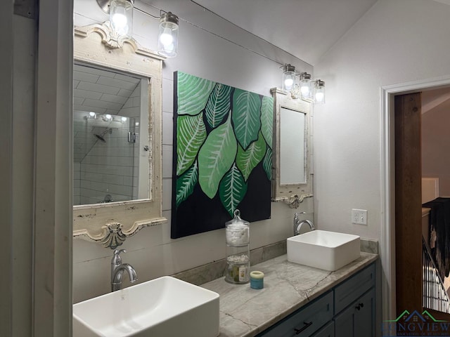 full bathroom featuring tiled shower, lofted ceiling, and a sink