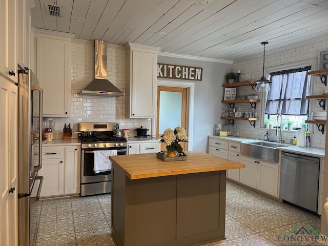 kitchen with a sink, open shelves, appliances with stainless steel finishes, butcher block counters, and wall chimney range hood