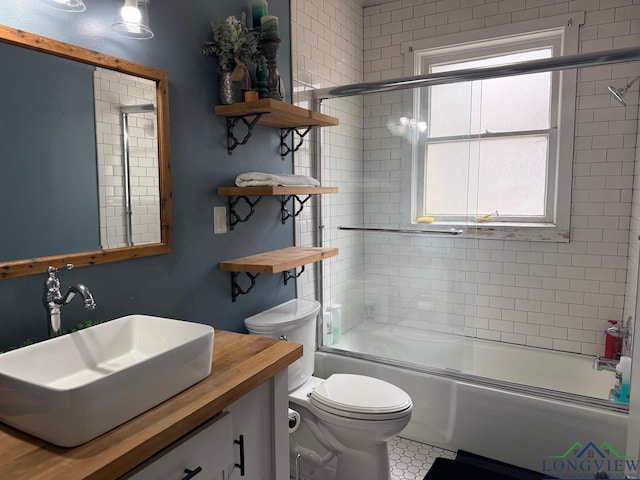 full bathroom featuring a wealth of natural light, toilet, vanity, and shower / bath combination with glass door