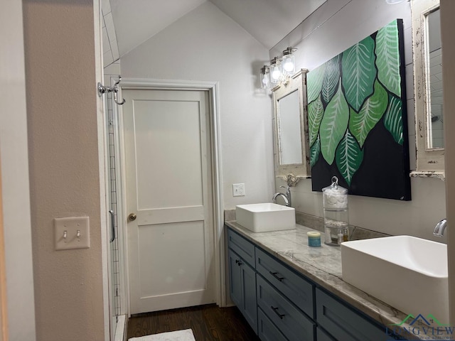 full bath featuring double vanity, vaulted ceiling, wood finished floors, and a sink