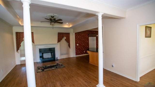 unfurnished living room featuring decorative columns, ceiling fan, dark hardwood / wood-style flooring, and ornamental molding