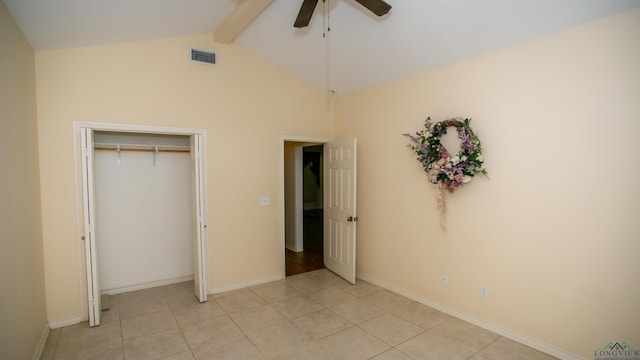 unfurnished bedroom with light tile patterned floors, vaulted ceiling with beams, a closet, and ceiling fan