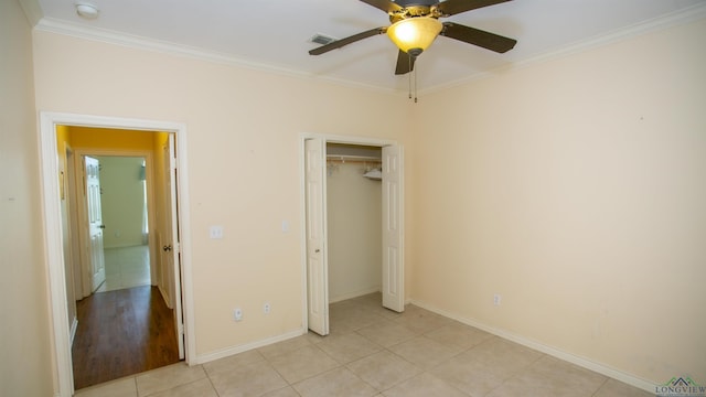 unfurnished bedroom featuring ceiling fan, light tile patterned floors, crown molding, and a closet