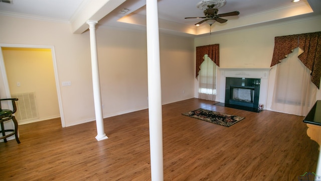 living room with ornate columns, ceiling fan, crown molding, a tray ceiling, and hardwood / wood-style flooring