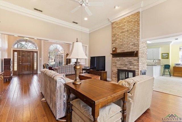 3314 Storey Lk, Tyler, TX 75707 - living area with crown molding, a ceiling fan, a brick fireplace, and light wood-style flooring