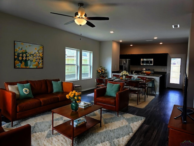 living room featuring ceiling fan and dark hardwood / wood-style floors