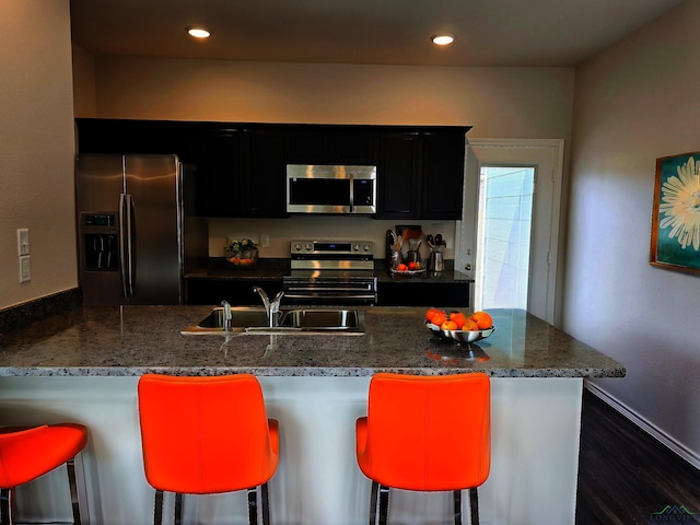 kitchen with a breakfast bar, kitchen peninsula, appliances with stainless steel finishes, and sink