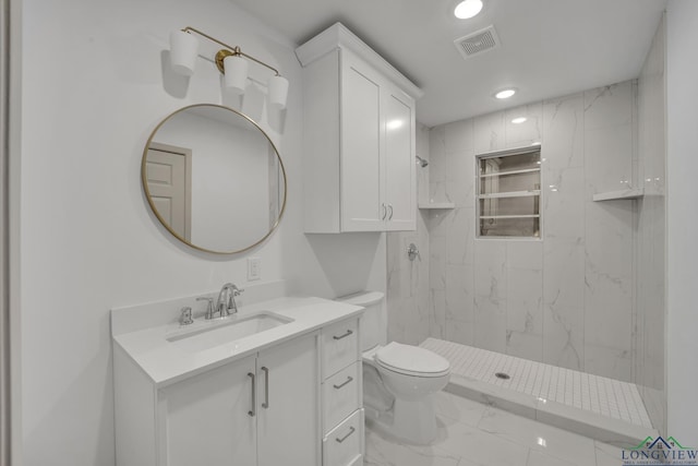 bathroom with a tile shower, vanity, and toilet