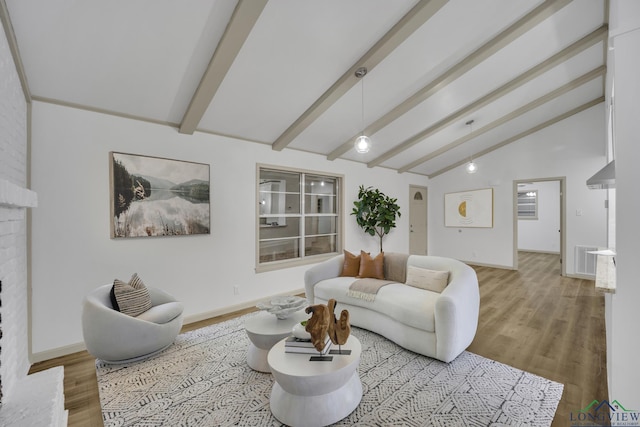 living room featuring lofted ceiling with beams, light hardwood / wood-style floors, and a fireplace