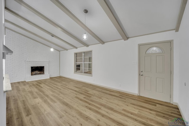 unfurnished living room with vaulted ceiling with beams, light wood-type flooring, and a brick fireplace