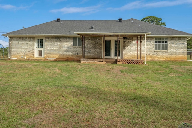 rear view of house with french doors and a lawn