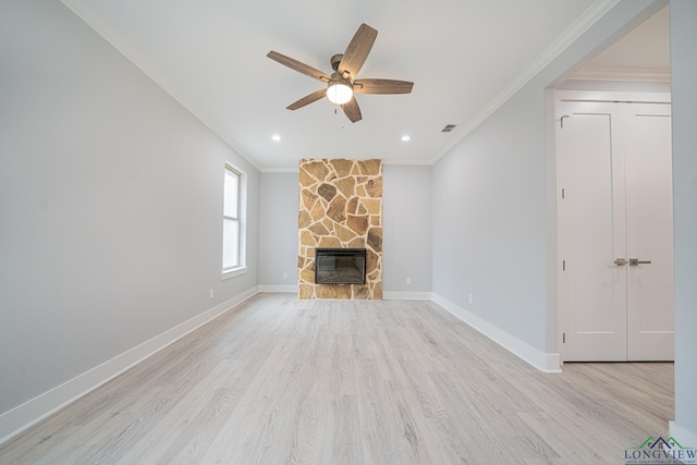 unfurnished living room featuring ornamental molding, a stone fireplace, ceiling fan, and light hardwood / wood-style flooring