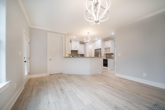 kitchen with crown molding, stainless steel fridge, white cabinetry, decorative backsplash, and kitchen peninsula