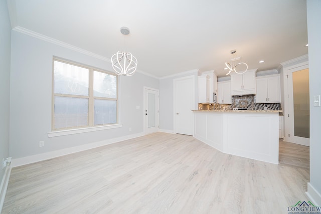 kitchen with white cabinetry, crown molding, a chandelier, light hardwood / wood-style floors, and backsplash