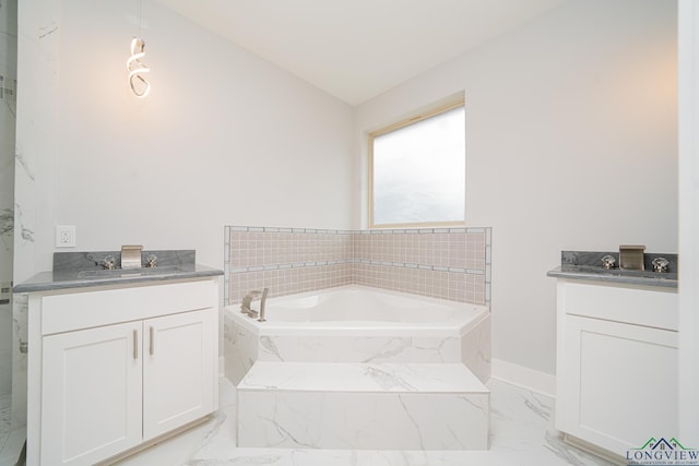 bathroom with a relaxing tiled tub, vanity, and vaulted ceiling