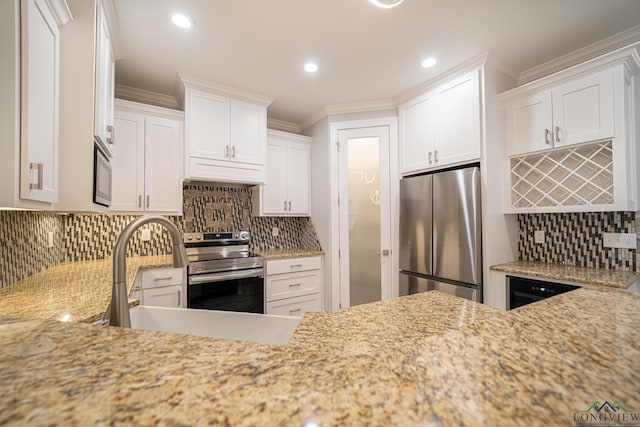 kitchen with sink, crown molding, stainless steel appliances, light stone countertops, and white cabinets