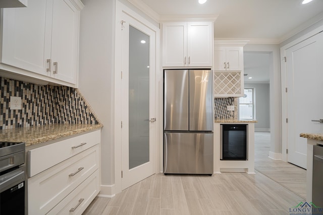 kitchen featuring white cabinetry, light stone counters, stainless steel refrigerator, beverage cooler, and decorative backsplash