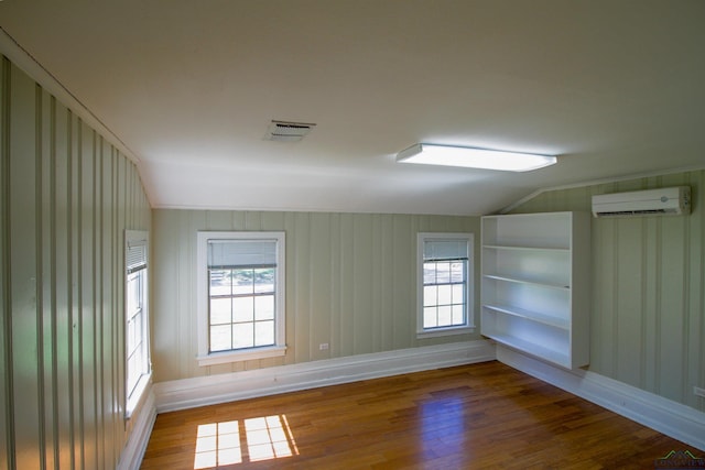 unfurnished room featuring wood-type flooring and an AC wall unit