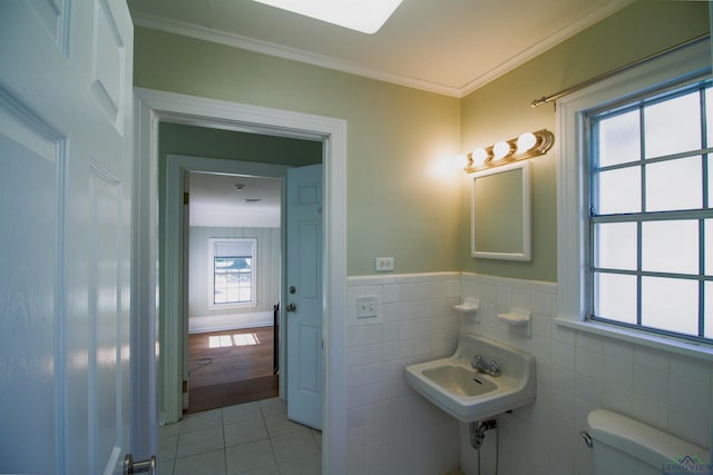 bathroom featuring tile patterned flooring, toilet, crown molding, and tile walls