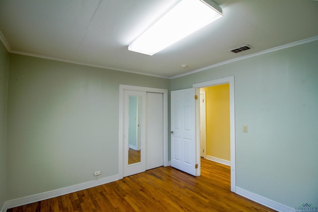 empty room with hardwood / wood-style flooring and crown molding