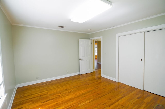 unfurnished bedroom featuring crown molding, a closet, and hardwood / wood-style flooring