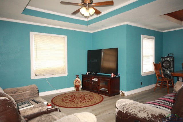 living room featuring hardwood / wood-style floors, ceiling fan, crown molding, and a tray ceiling