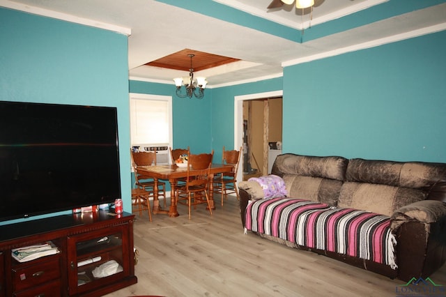 living room featuring light hardwood / wood-style floors, a raised ceiling, cooling unit, and a notable chandelier