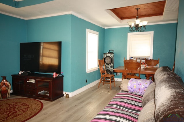 living room with a chandelier, a tray ceiling, light hardwood / wood-style flooring, and crown molding