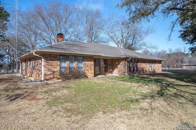 single story home featuring a shingled roof, a chimney, a front lawn, and brick siding