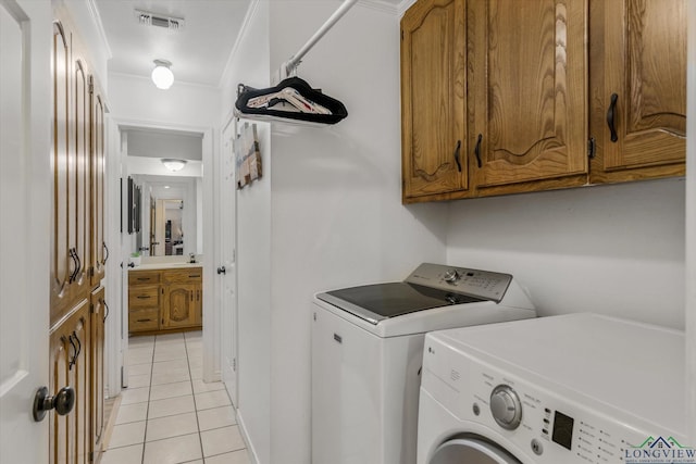 laundry area featuring light tile patterned floors, washing machine and dryer, visible vents, cabinet space, and crown molding