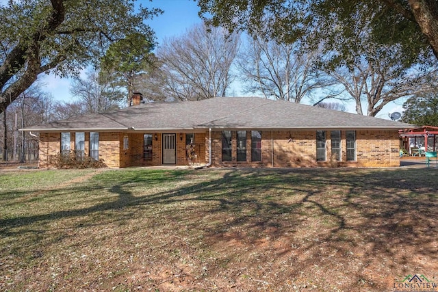 view of front of property with a front yard, brick siding, a chimney, and roof with shingles