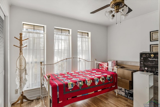 bedroom featuring a ceiling fan, multiple windows, and light wood finished floors