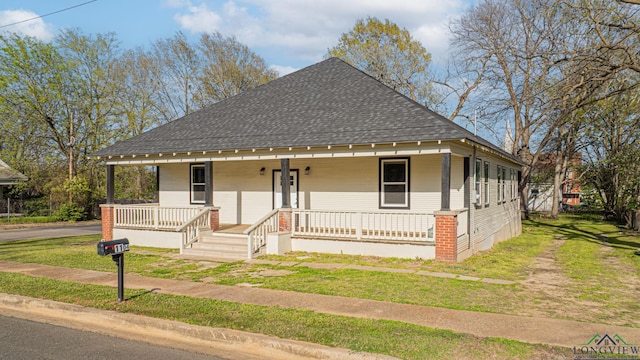 1104 N Bolivar St, Marshall, TX 75670 - view of front of house with a front lawn, a shingled roof, and covered porch
