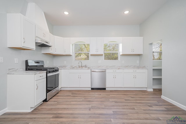1104 N Bolivar St, Marshall, TX 75670 - kitchen with white cabinetry, stainless steel appliances, under cabinet range hood, a sink, and light wood-style floors