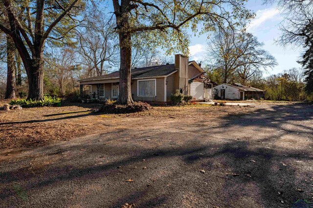 view of property exterior with a chimney and dirt driveway