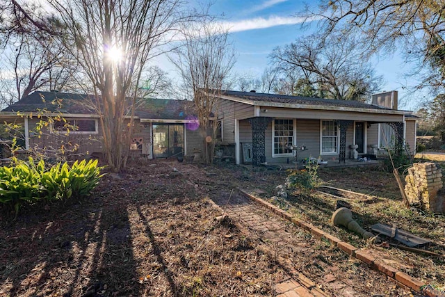 back of house with covered porch and a chimney