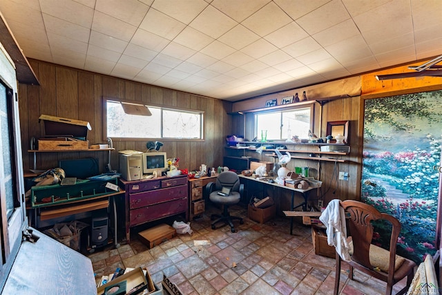 home office featuring wooden walls and brick patterned floor