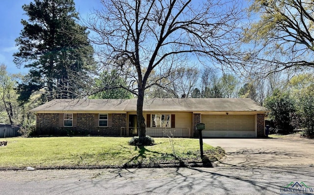 single story home with a front lawn, an attached garage, driveway, covered porch, and brick siding