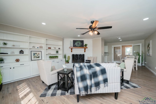 living room with a fireplace, light hardwood / wood-style floors, and ceiling fan